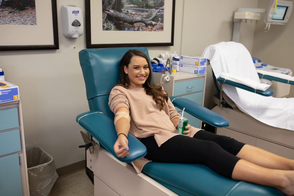 Teenage girl smiles and holds a soda after giving blood